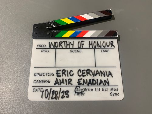 A picture of our slate with our production name 'Worthy of Honour' written on it as well as our director Eric Crevania and Camera Amir Emadian written on below with the date