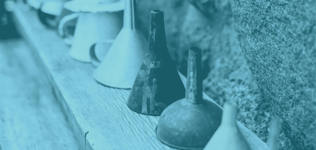 Funnels lined up in a row on a wooden shelf.