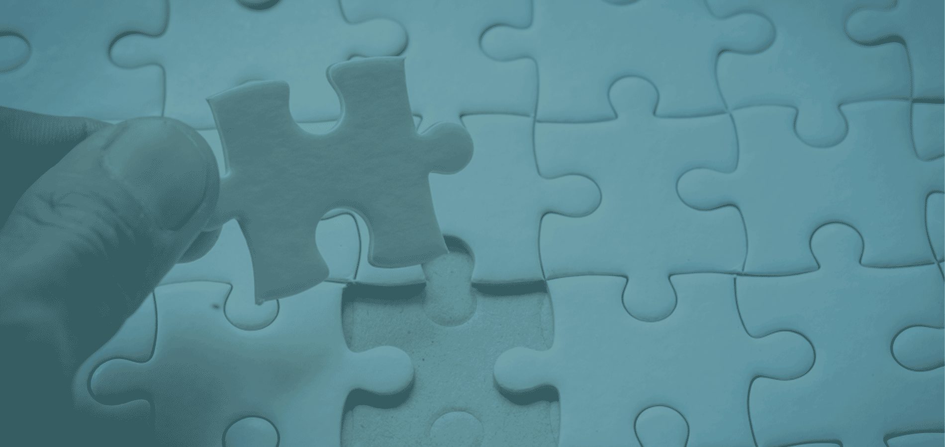 A hand placing a puzzle piece into its corresponding spot. 