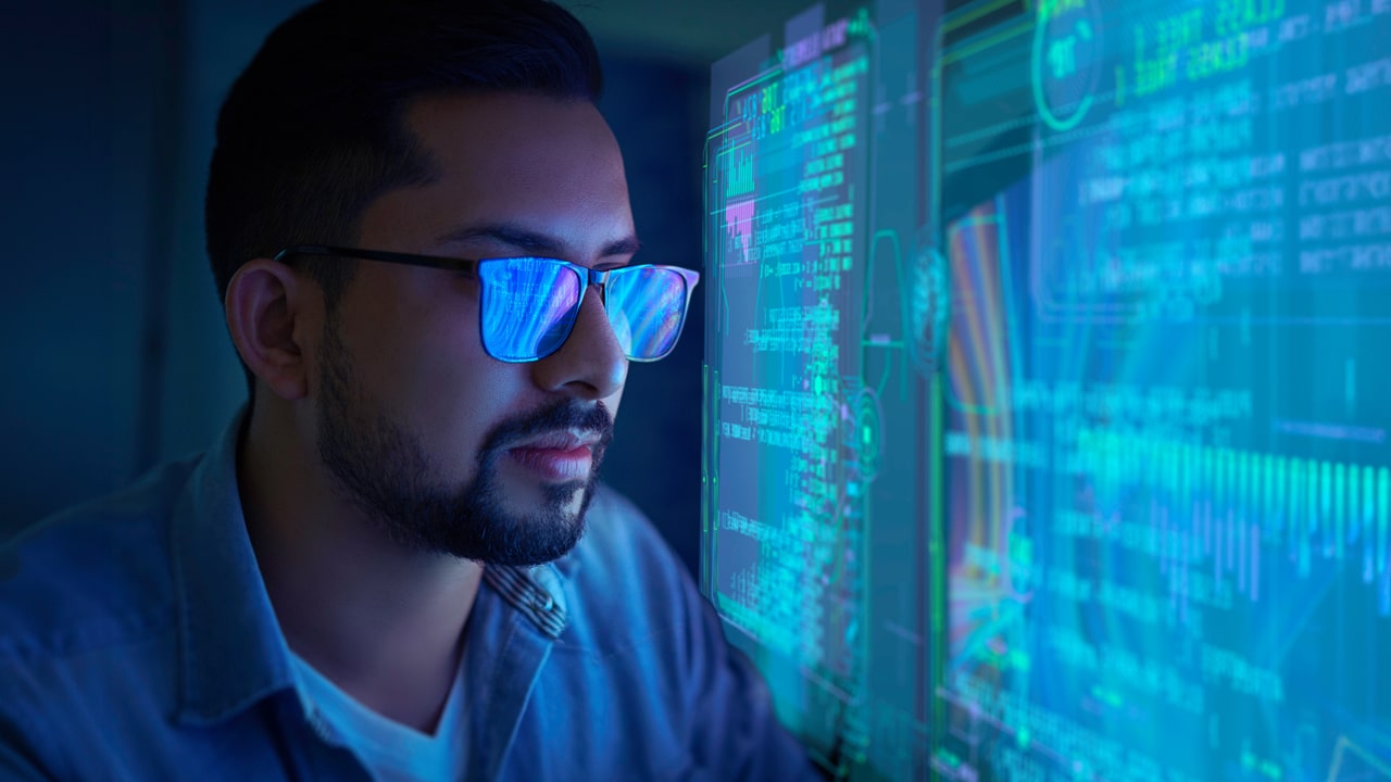 A man looks at a large screen of data