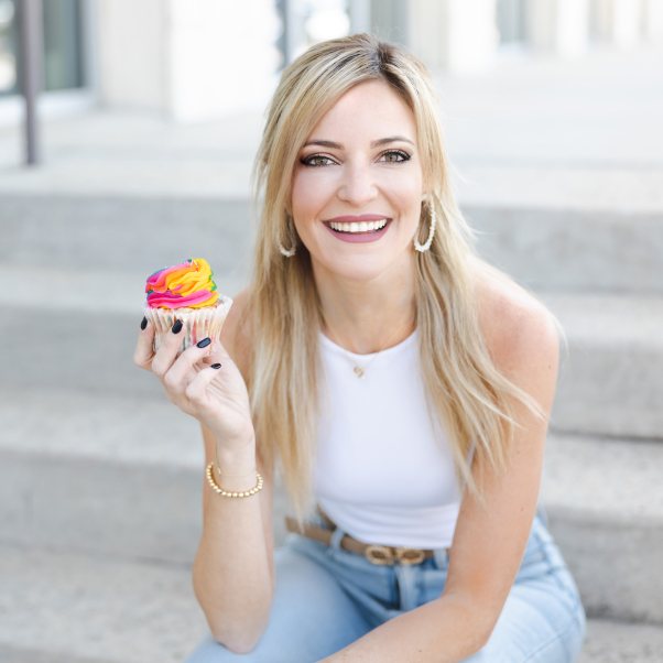 a woman sitting on the steps holding a cupcake