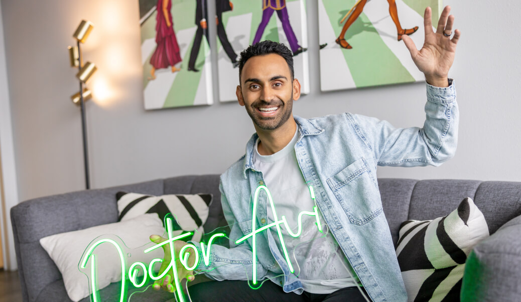 a man sitting on a couch holding a neon sign
