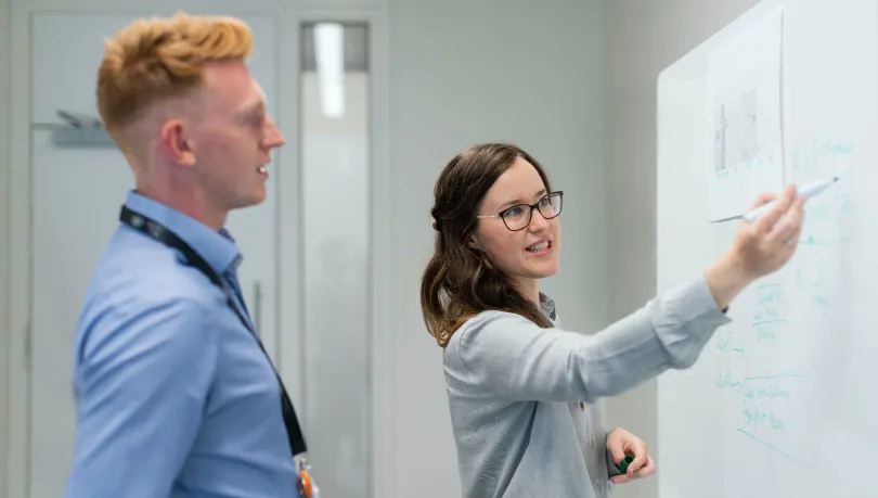 a man and a woman standing in front of a whiteboard