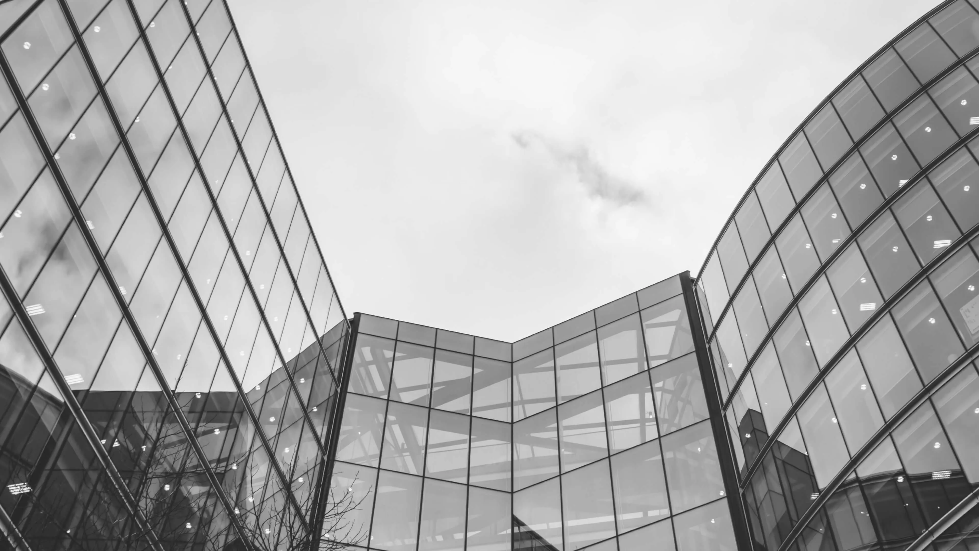 Curved building reflecting clouds in a grayscale photo.