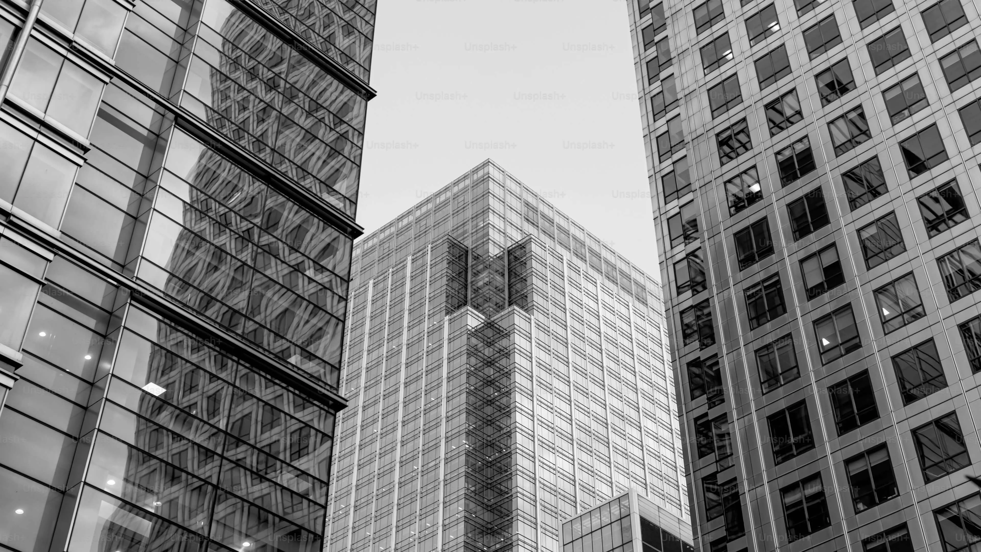 Black and white image of modern skyscrapers with reflective glass facades, featuring a building with a distinct architectural cutout.