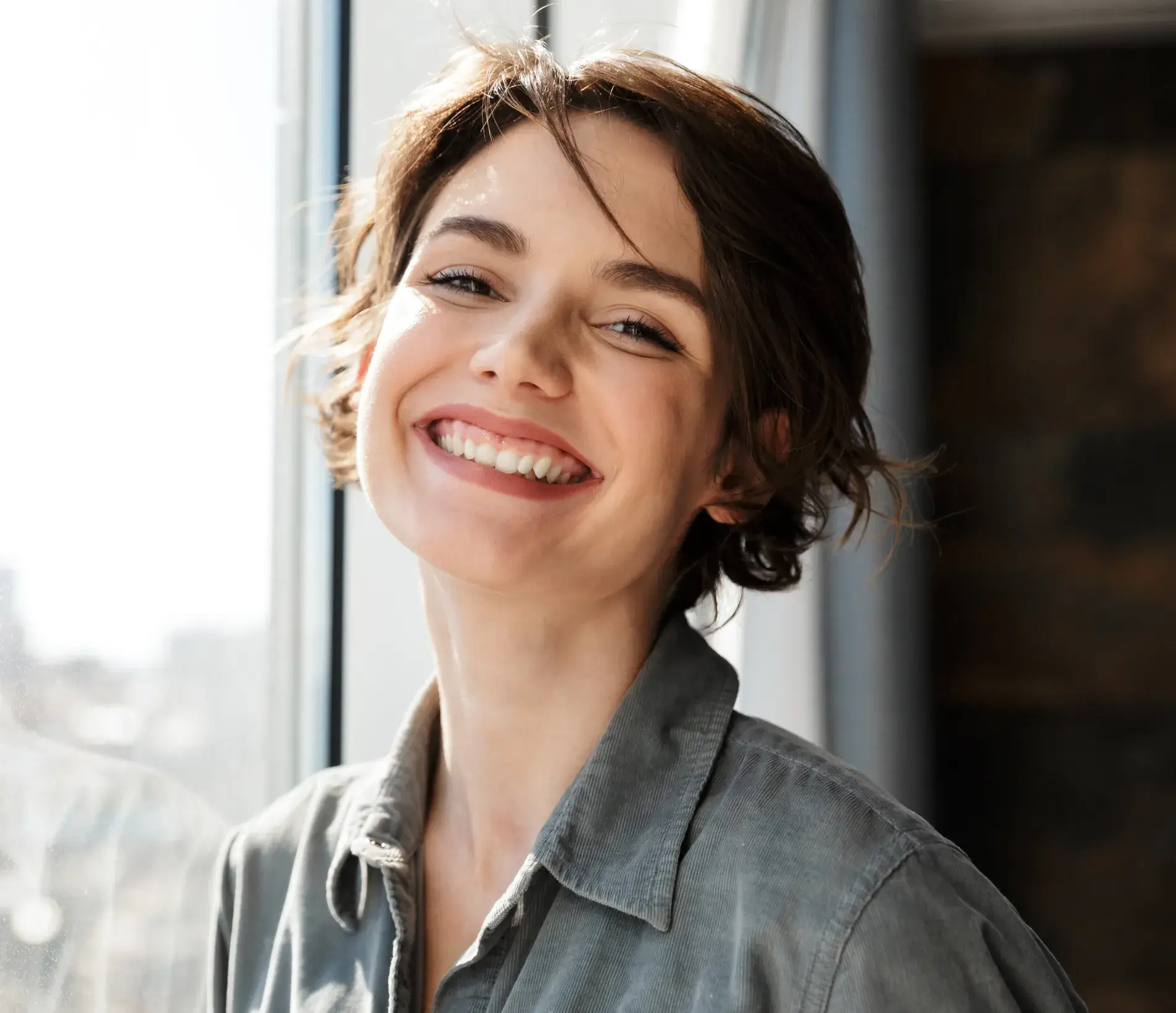 A woman smiling in front of a window.