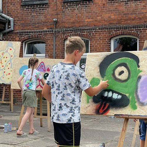 Kinder beim Sprühen während des Graffitiworkshops