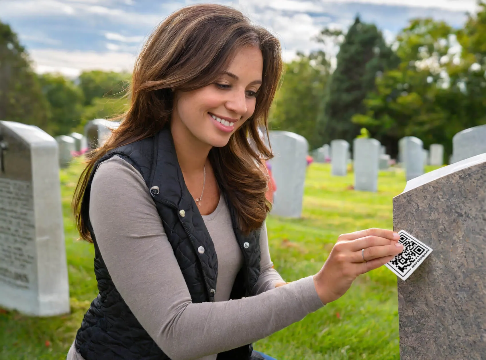 Woman placing memorial QR plaque onto headstone