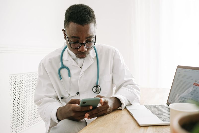 man in a medical gown using a smartphone to access an online learning management system