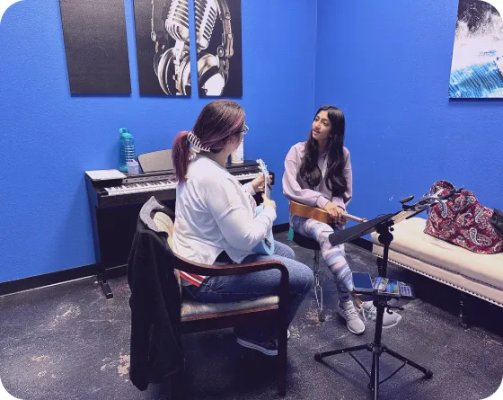 A teacher in a class room with her student is teaching to play ukulele