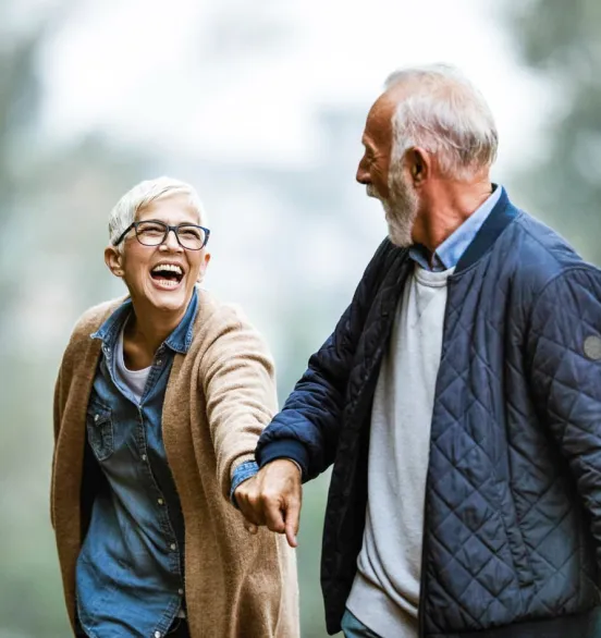 older couple hold hands in a street laughing