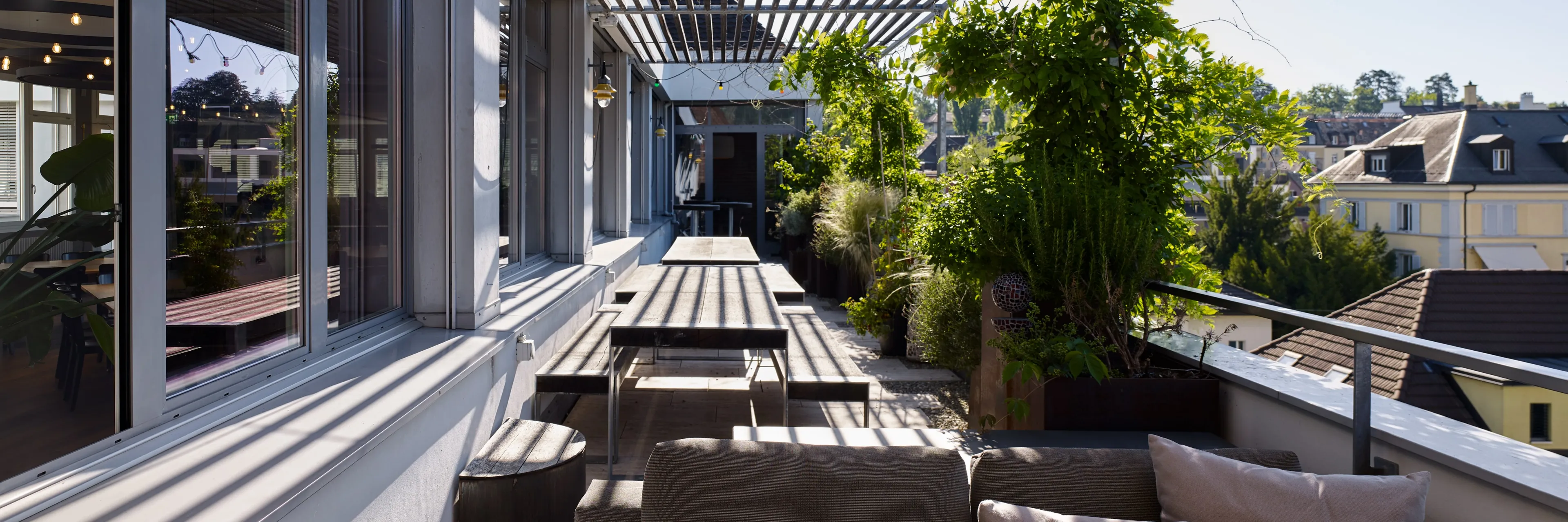 Sunny terrace at Ginetta Workspace, equipped with an outdoor communal table, perfect for enjoying lunches and breaks in the sunshine, providing a refreshing outdoor setting for members.