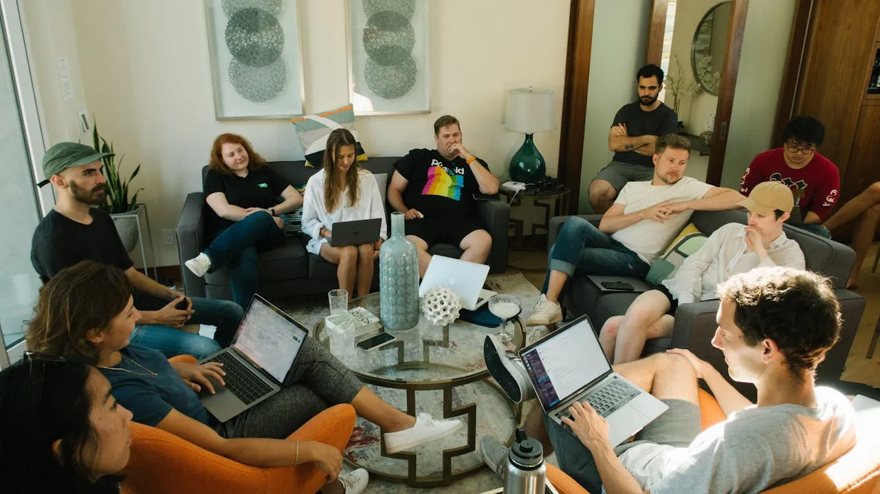 A group of people sitting in a living room with laptops.