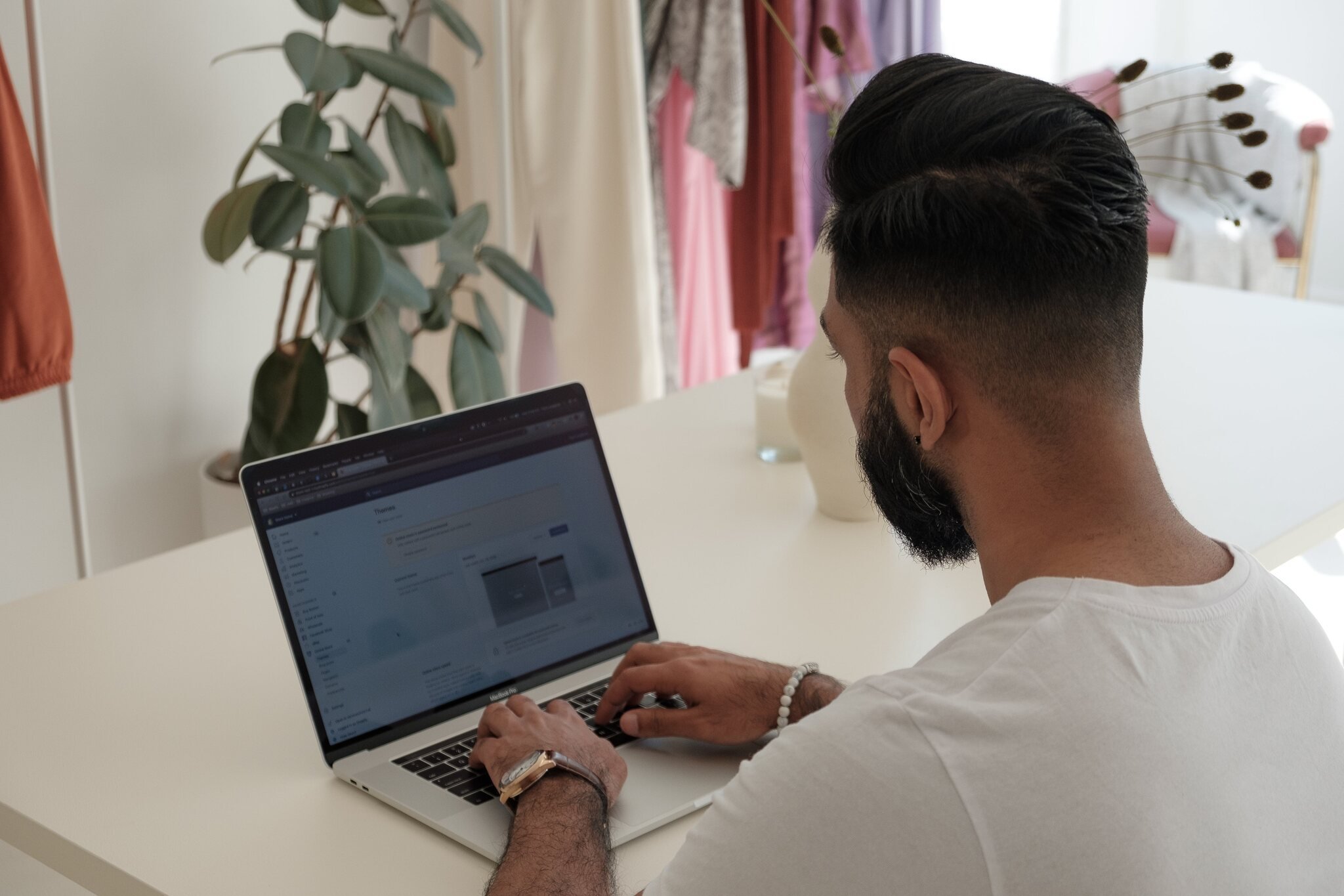 over shoulder man organizing a Shopify store on a laptop