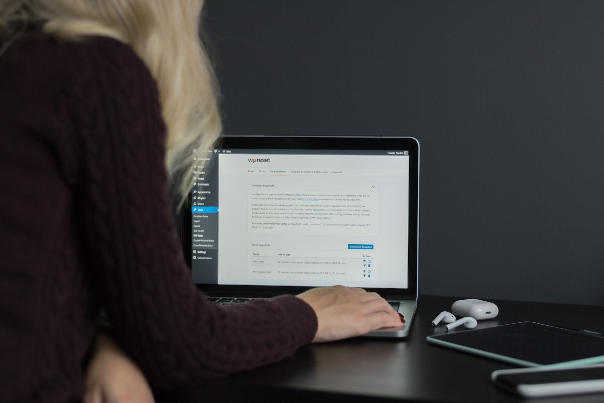 person using MacBook Pro on brown wooden table checking WordPress