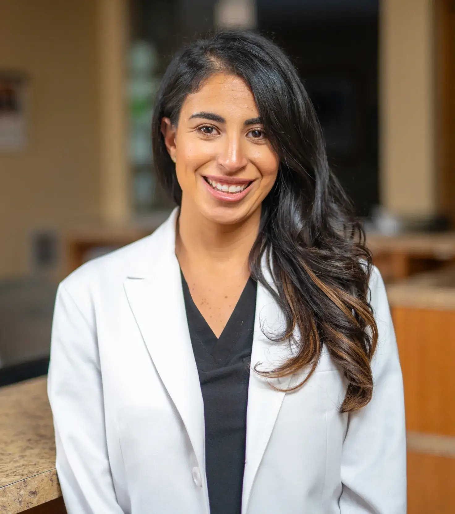 A woman in a white jacket standing in front of a counter.