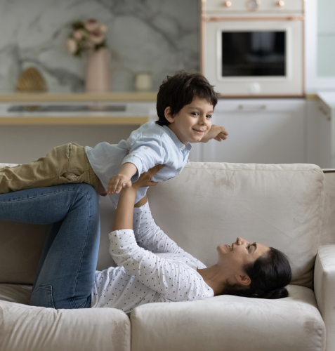 A woman with brown hair is on the couch with a child with brown hair.