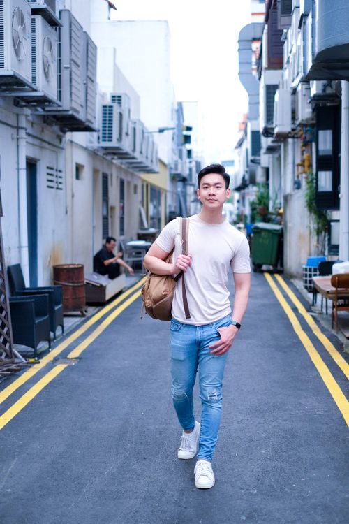 Picture of Matheus Ting (Asian actor, singer, dancer), photographed in the back alleys of South East Asia, with a backpack. Street fashion photography style.