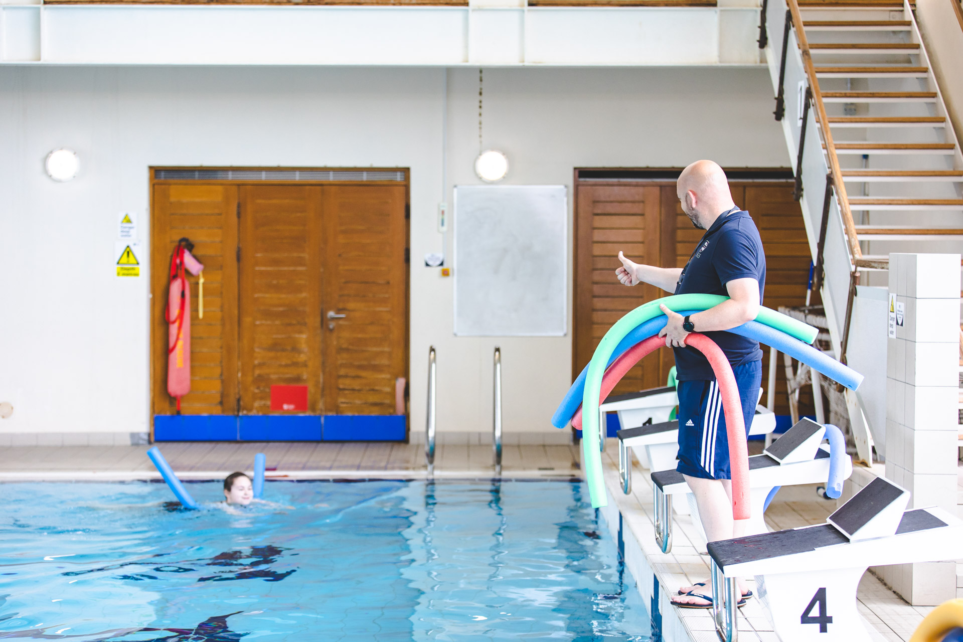 A picture of a volunteer looking after a child in a swimming pool