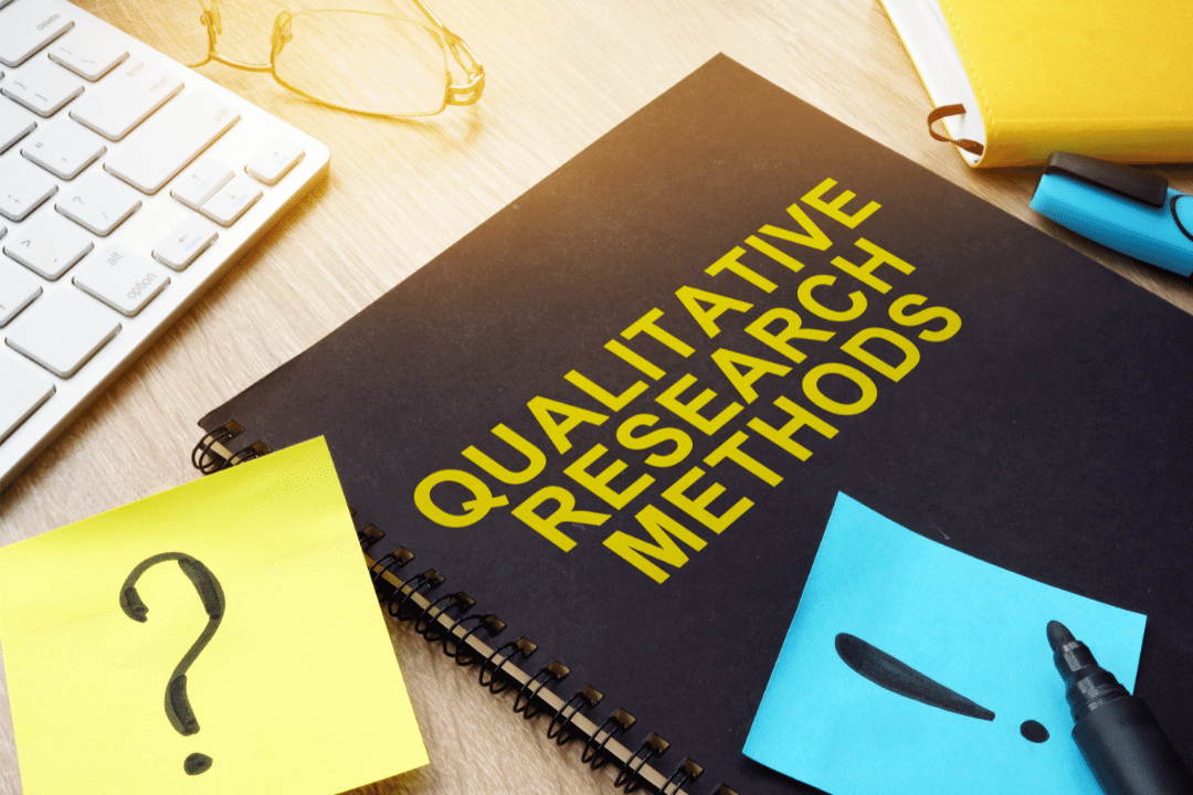 large black notebook with sticky notes displaying qualitative research methods