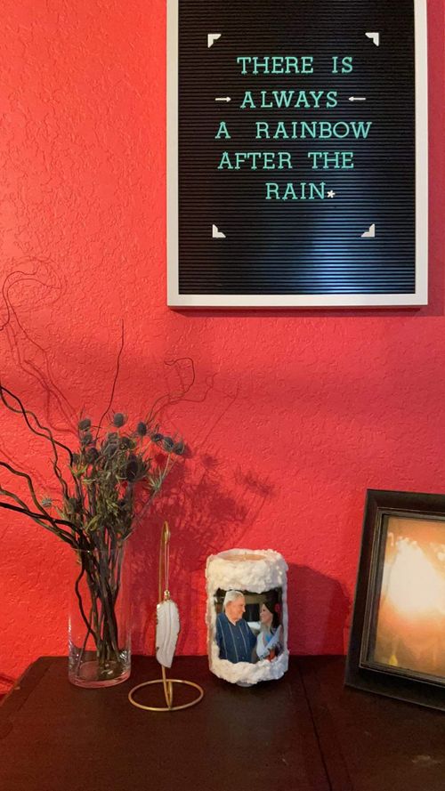 This featured candle sits on a small table with a orange-red wall in the background.