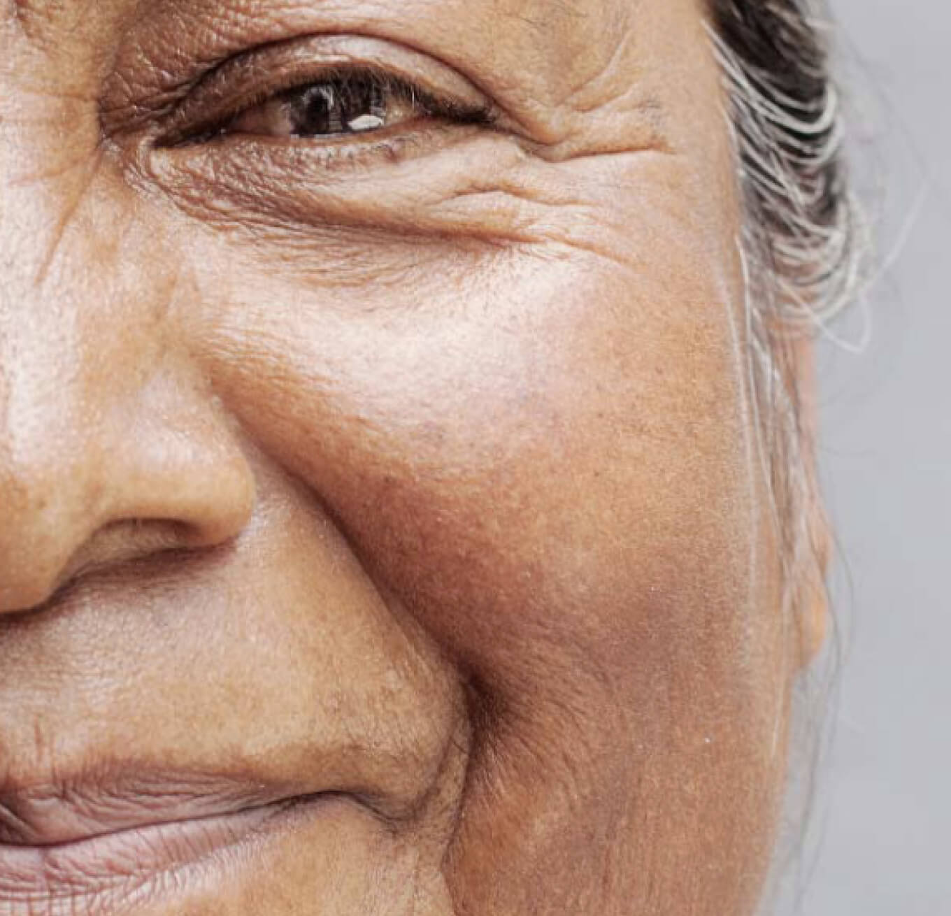 A close up of a person smiling at the camera while sitting in a warm room.