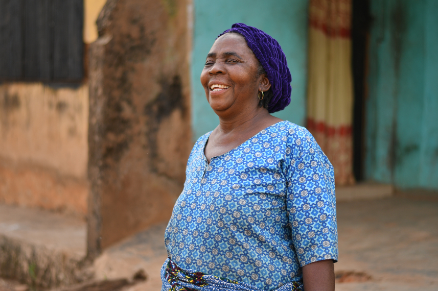 A mama wearing a blue cap and top, laughing and staring at the camera