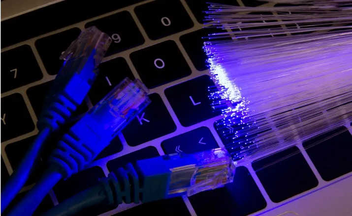 Internet cables and optic fiber on top of a laptop keyboard